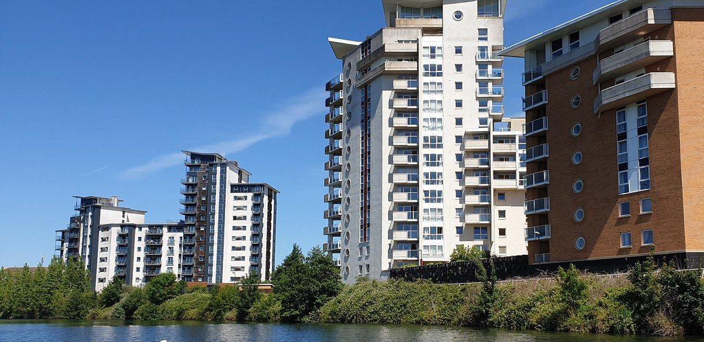 Century Wharf: The whole Century Wharf river frontage from a boat on the Taff — blue sky, the full run of blocks